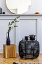 Stylish concept at living room interior with black rattan coffee table, round mirror, flowers in vase, lantern, shelf, wooden cube