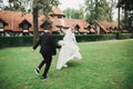 Stylish couple of happy newlyweds. Bride running from groom in the park on their wedding day with bouquet Royalty Free Stock Photo