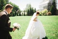 Stylish couple of happy newlyweds. Bride running from groom in the park on their wedding day with bouquet Royalty Free Stock Photo