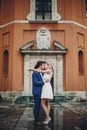 Stylish couple  kissing in european city street on background of old architecture. Fashionable bride and groom in love enjoying Royalty Free Stock Photo