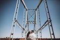 stylish couple in love hugging and kissing on bridge in the summer city. modern woman and man in fashionable white clothes Royalty Free Stock Photo