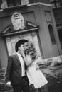 Stylish couple walking and kissing in european city street on background of old architecture. Fashionable bride and groom in love Royalty Free Stock Photo