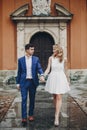 Stylish couple walking together in european city street on background of old architecture. Fashionable bride and groom in love Royalty Free Stock Photo