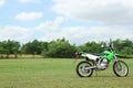 Stylish cross motorcycle on green grass outdoors, space for text