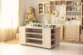 Stylish cuisine with decorated Christmas tree and gifts. Wooden kitchen in winter decor.