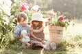 Stylish cute children boy and girl sit near peonies flowers