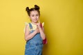 Stylish smiling happy primary school student girl in casual denim with pink rucksack, showing index finger at camera