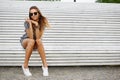 Stylish cute young woman sitting on a bench in a summer park