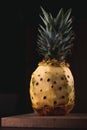 Stylish dark photography of a pineapple on a wooden chopping board. Pineapple with the top, and the bottom, but peeled on the midd