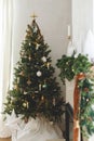 Stylish decorated christmas tree with vintage baubles and modern decor on fireplace mantel with bells and ribbon. Modern
