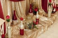 stylish decorated golden bottles of wine with red flowers, luxury rustic decor for wedding ceremony and reception Royalty Free Stock Photo