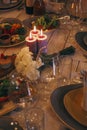 Stylish delicious table with food and drinks, burning candles and flowers bouquet at evening wedding reception. Christmas feast or Royalty Free Stock Photo