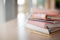 Stylish designed coral and white coloured stack of diaries with gold pen.