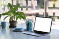 Designer workstation with laptop computer with blank screen and stationery on white table.