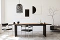 Stylish dining room interior with design wooden family table, black chairs, teapot with mug, mock up art paintings on the wall.