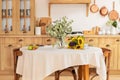 Stylish dining room with wooden table and chairs. Cozy cuisine  decorated with summer decor and  table setting summer flowers and Royalty Free Stock Photo