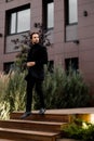 Stylish dressed businessman is walking down by stairs, looking at the side, posing for photo outdoor. Successful Royalty Free Stock Photo