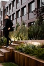 Stylish dressed businessman is walking down by stairs, looking at the side, posing for photo outdoor. Successful Royalty Free Stock Photo