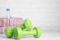 Stylish dumbbells, towels and water on table against brick wall, space for text Royalty Free Stock Photo