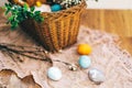 Stylish Easter eggs at easter bread cake, ham, beets, sausage, butter, green and willow branches in wicker basket on rustic fabric Royalty Free Stock Photo