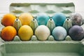 Stylish easter eggs in carton tray on white wooden background. Modern colorful easter eggs painted with natural dye in different Royalty Free Stock Photo