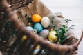 Stylish easter eggs on cloth in rustic basket on white wooden background. Easter hunt concept. Modern easter eggs painted with