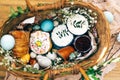 Stylish Easter eggs, easter bread cake, ham, beets, sausage, butter, green branches in wicker basket on rustic fabric with spring Royalty Free Stock Photo