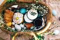 Stylish Easter eggs, easter bread cake, ham, beets, sausage, butter, green branches in wicker basket on rustic fabric with spring Royalty Free Stock Photo