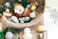 Stylish Easter eggs, easter bread cake, ham, beets, sausage, butter, green branches in wicker basket on white wooden background Royalty Free Stock Photo