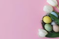 Stylish easter eggs in nest and flowers flat lay on pink background. Natural dyed colorful eggs, feathers nest and tulips. Royalty Free Stock Photo
