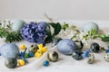 Stylish easter eggs and spring flowers on rustic wooden table. Happy Easter! Natural dye marble and blue eggs, purple hiacynt