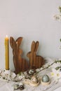 Stylish easter eggs, wooden bunnies, cherry blossom and candle composition on rustic table. Happy Easter! Modern natural dyed Royalty Free Stock Photo