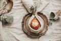 Stylish Easter flat lay, table setting with egg in easter bunny napkin. Modern natural dyed egg on napkin with bunny ears, flowers