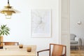 Stylish and eclectic dining room interior with mock up poster map, sharing table design chairs, gold pedant lamp and elegant sofa Royalty Free Stock Photo