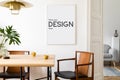 Stylish and eclectic dining room interior with mock up poster map, sharing table design chairs, gold pedant lamp and elegant sofa. Royalty Free Stock Photo