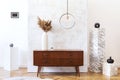 Stylish and eclectic interior of living room with design retro cabinet, round pendant lamp, marble cubes and elegant accessories.