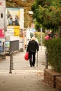 Stylish elderly woman in a black jacket strolls with a red bag in an urban setting