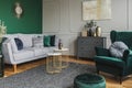 Stylish emerald green and grey living room interior design with abstract painting on the wall