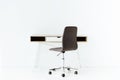 stylish empty work table and wheeled chair in front of