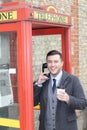 Stylish ethnic gentleman calling from vintage payphone Royalty Free Stock Photo