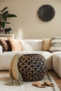 Stylish ethnic living room interior with design modular sofa, rattan basket with blanket, carpet decor, decoration.