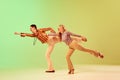 Stylish, expressive, talented young man and woman in vintage clothes dancing against gradient green yellow background