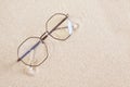 stylish eye glasses in a round metal frame on the sand Royalty Free Stock Photo