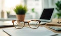 Stylish eyeglasses on desk with documents and laptop in modern office setting Royalty Free Stock Photo