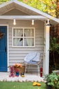 Stylish fall decor on front veranda home. Autumn wooden porch home. Cozy Autumn terrace with chair, plaid, rubber boots, baskets w Royalty Free Stock Photo