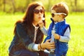 Stylish family concept. Portrait of fashionable baby boy and his gorgeous mother in trendy eyewear playing with dandelion in the Royalty Free Stock Photo