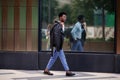 Stylish fashion African American man walks outdoors in the city, wearing blue trousers, shirt And a black leather jacket Royalty Free Stock Photo