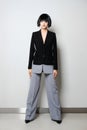 Stylish fashion model in short black wig posing in double color pantsuit with wide trousers and jacket with deep cut