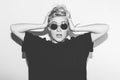 Stylish fashion blonde bad girl surprised holding her head. Dressed in black t-shirt and rock sunglasses. Dangerous Royalty Free Stock Photo