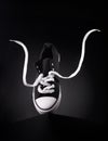 Stylish and fashion shot of a classic black and white sneaker with levitating in air laces. Shoes on dark background Royalty Free Stock Photo